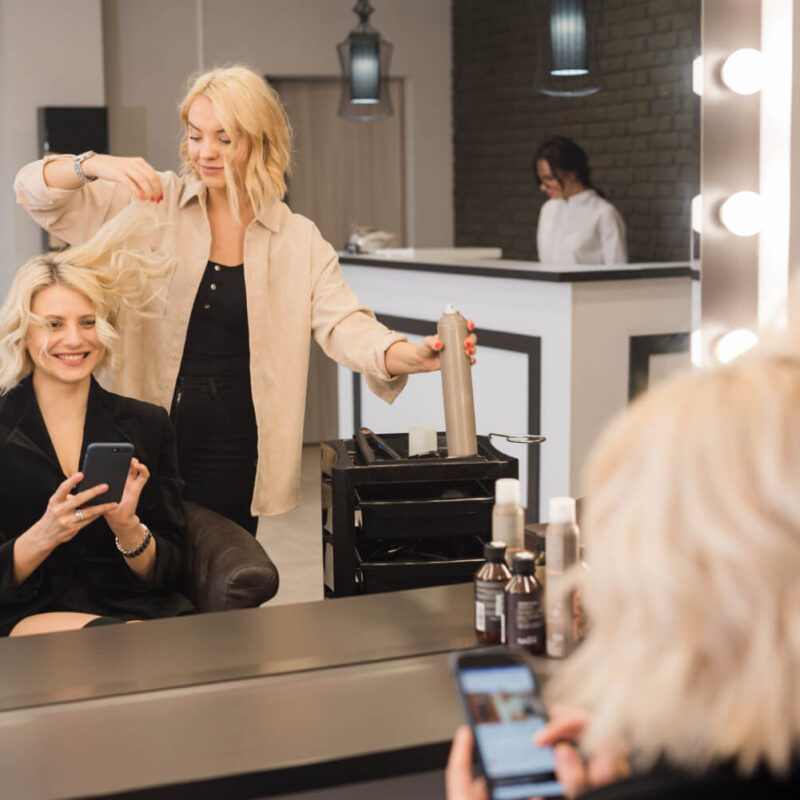 blonde-woman-with-mobile-phone-getting-her-hair-done